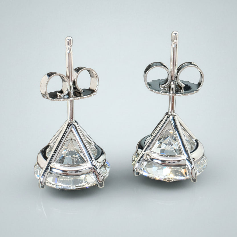 Pair of silver earrings with clear gemstones on a light gray background
