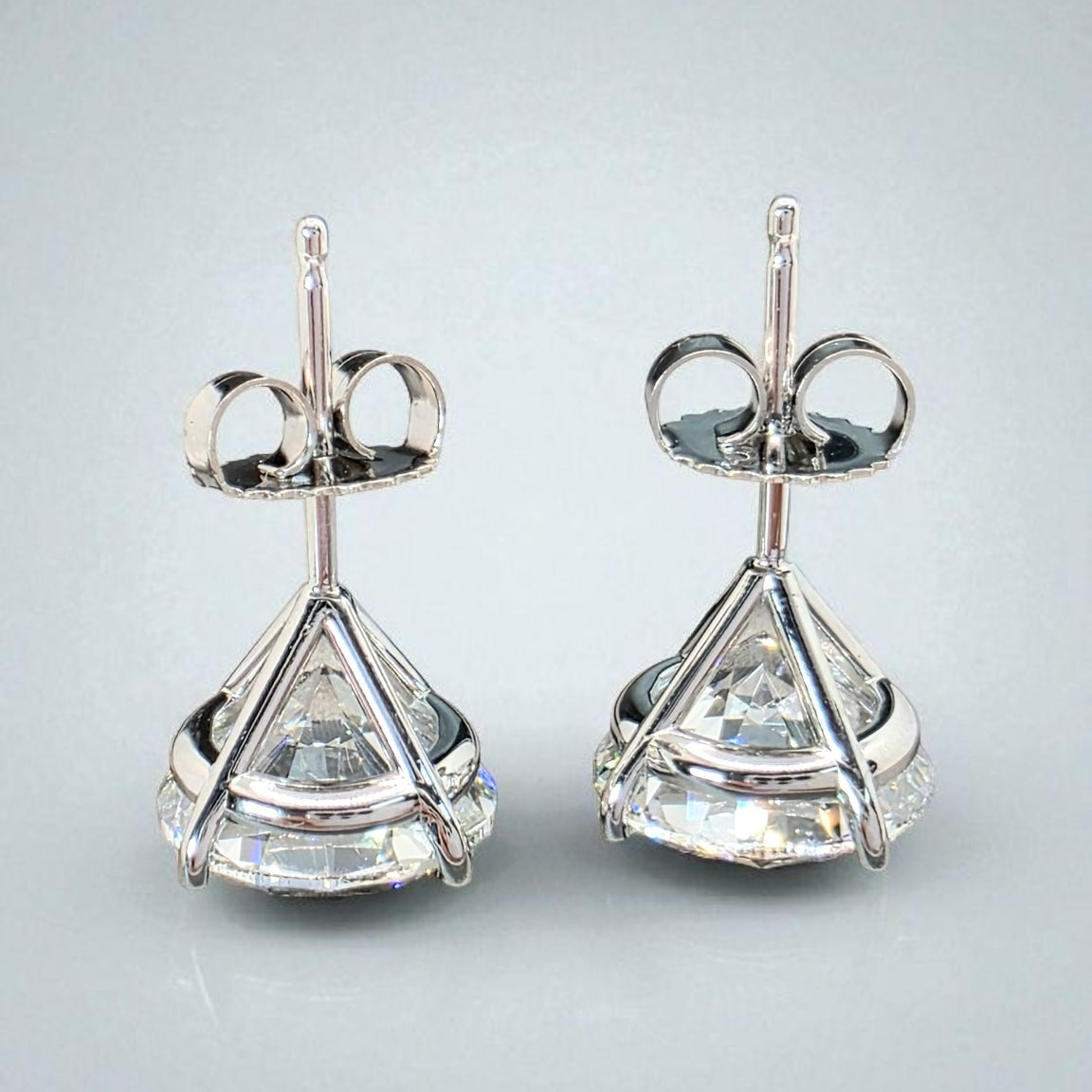 Pair of silver earrings with clear gemstones on a light gray background