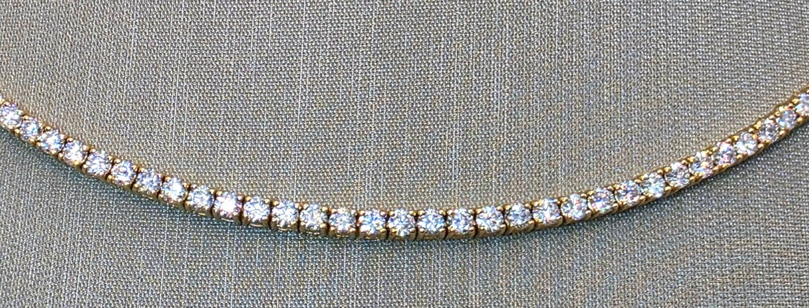 Close up of continuously set round brilliant lab grown diamonds in a 14K yellow gold eternity tennis necklace