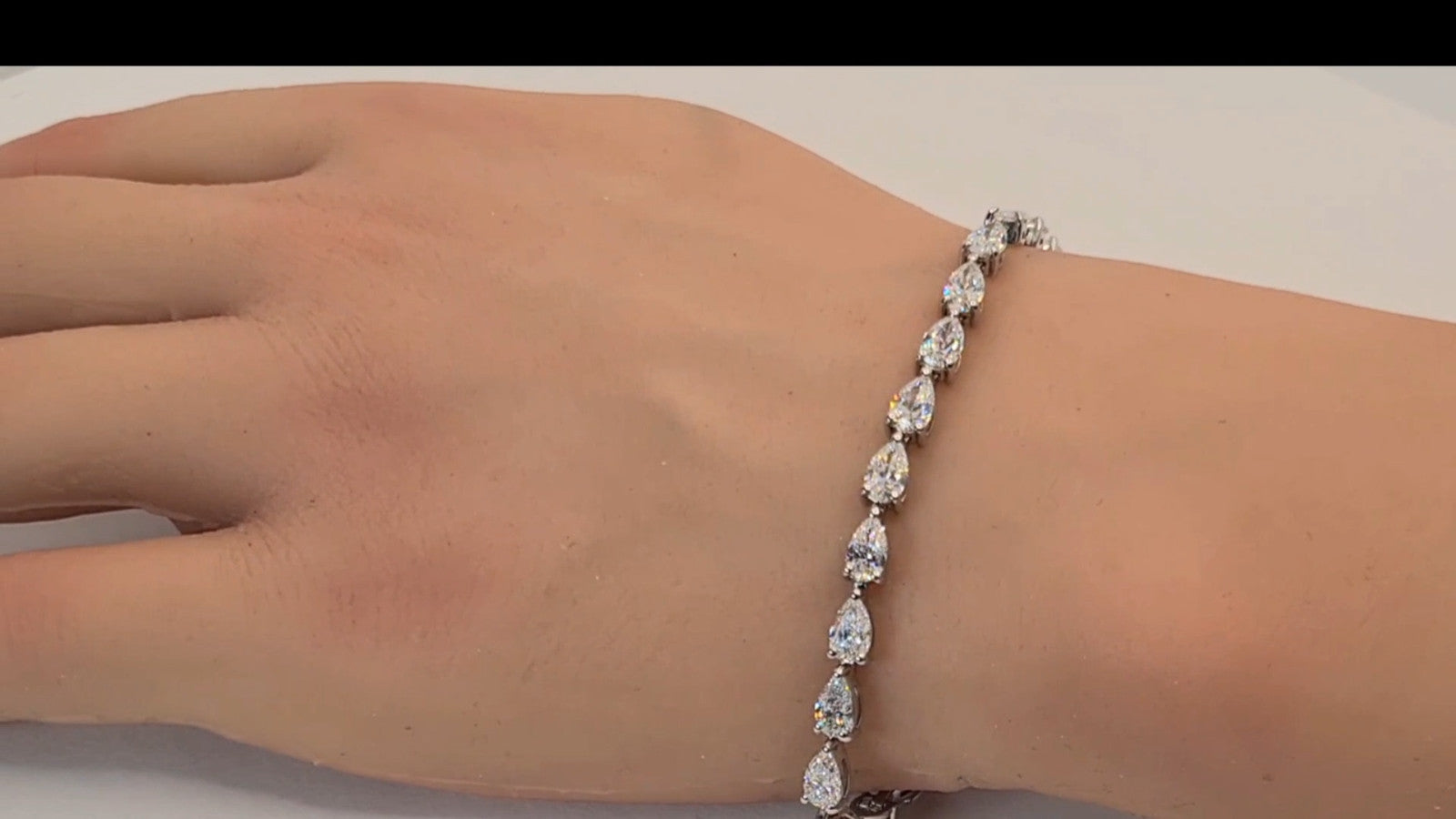 Pear shape lab grown diamond tennis bracelet shown on the hand and wrist in 14K white gold