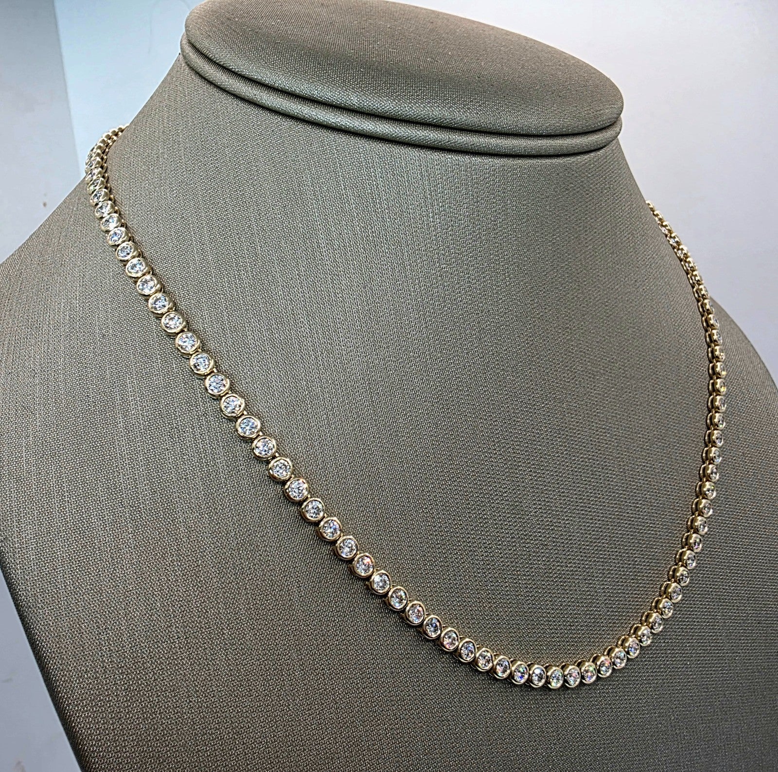 Angled view of a bezel set lab grown diamond tennis necklace in 14K yellow gold