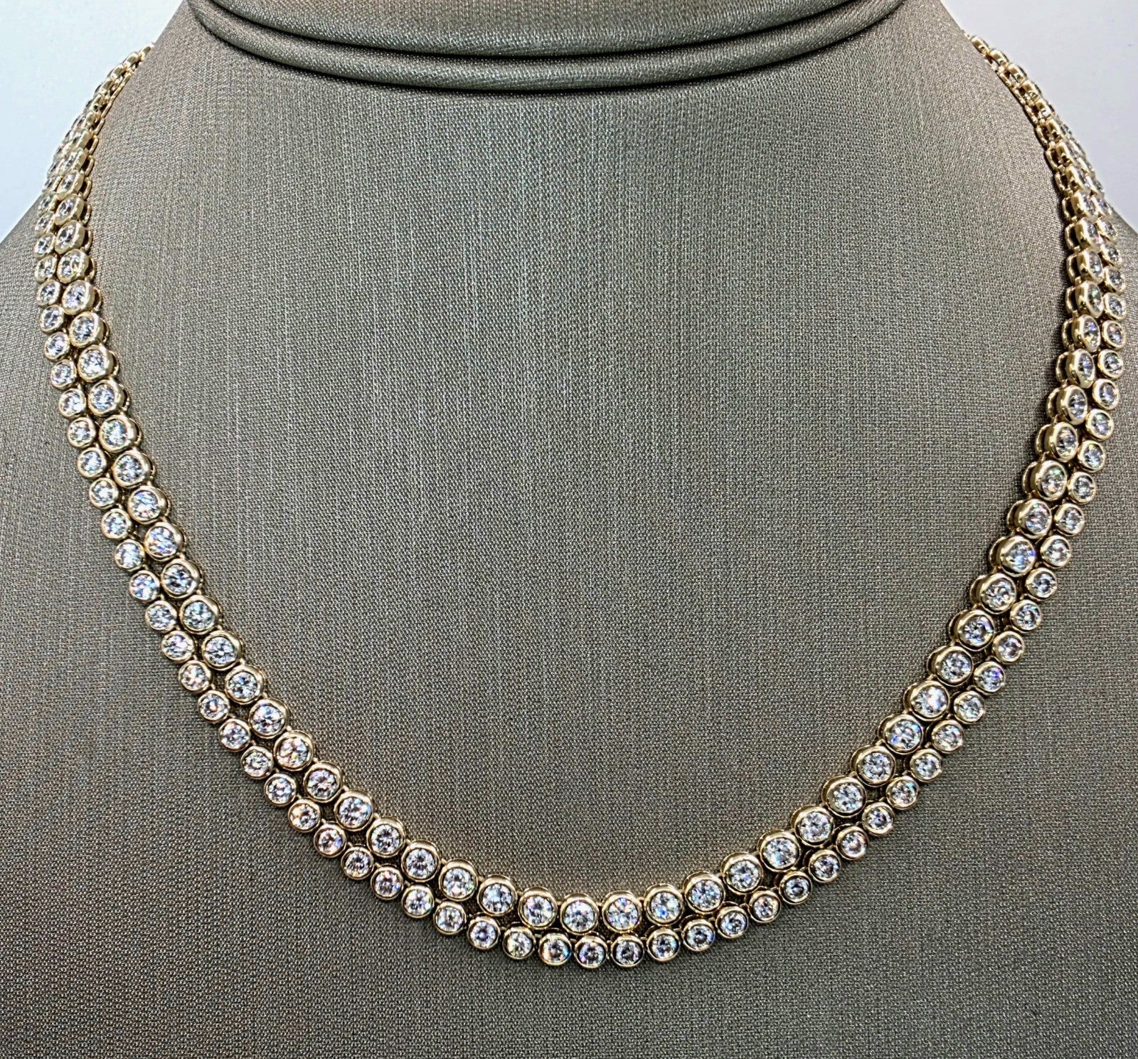 Close up of bezel set round brilliant lab grown diamonds in a 14K yellow gold tennis necklace
