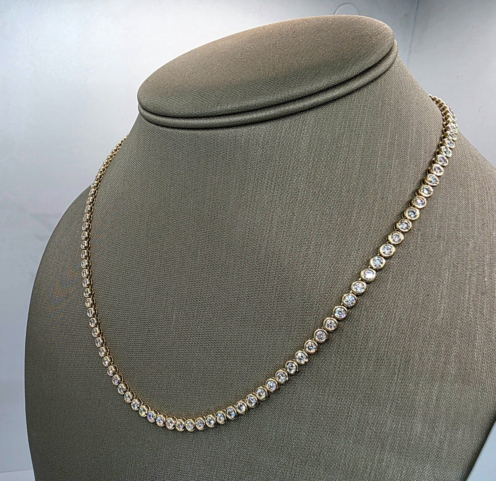 Bezel set lab grown diamond tennis necklace shown on a display bust, 14K yellow gold